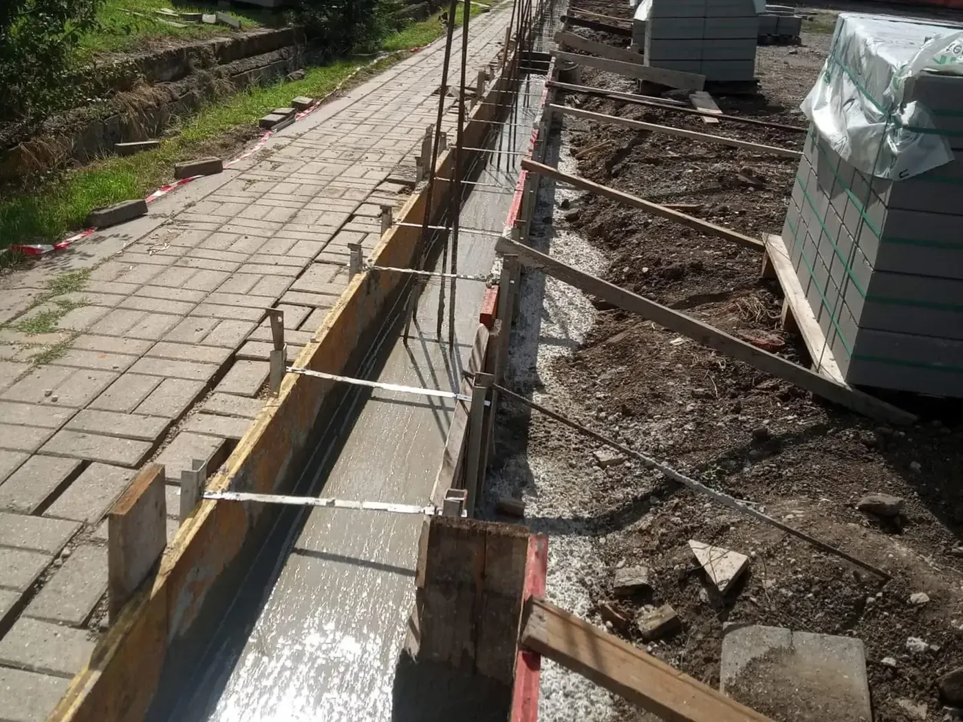 Díszzsalukő kerítés sávalapjának zsaluzata és kitűzése járdaszegély mellett