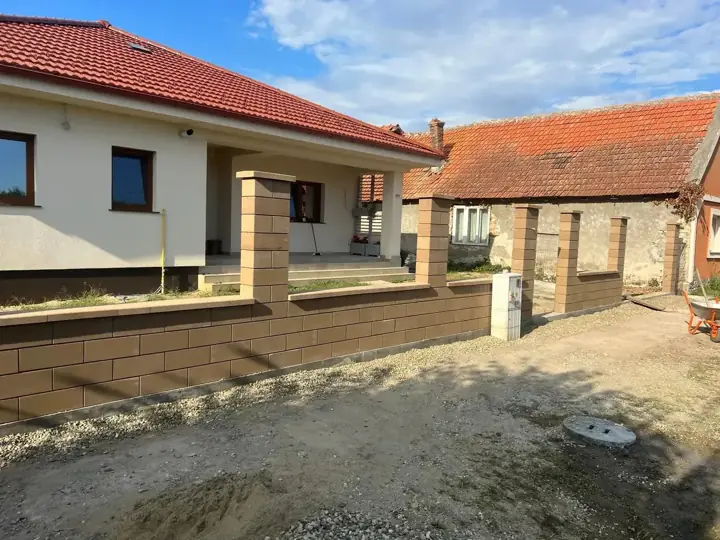 Bézs-barna díszzsalukő kerítés lábazat és pillérek kertes ház előtt